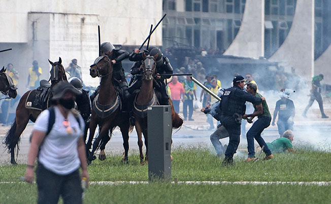 警方发射催泪弹后，骑警在烟雾中挥棍驱赶示威者。（法新社）