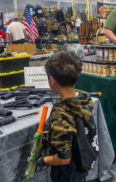 拿着玩具枪的小孩入迷的看着真枪实弹。（法新社）