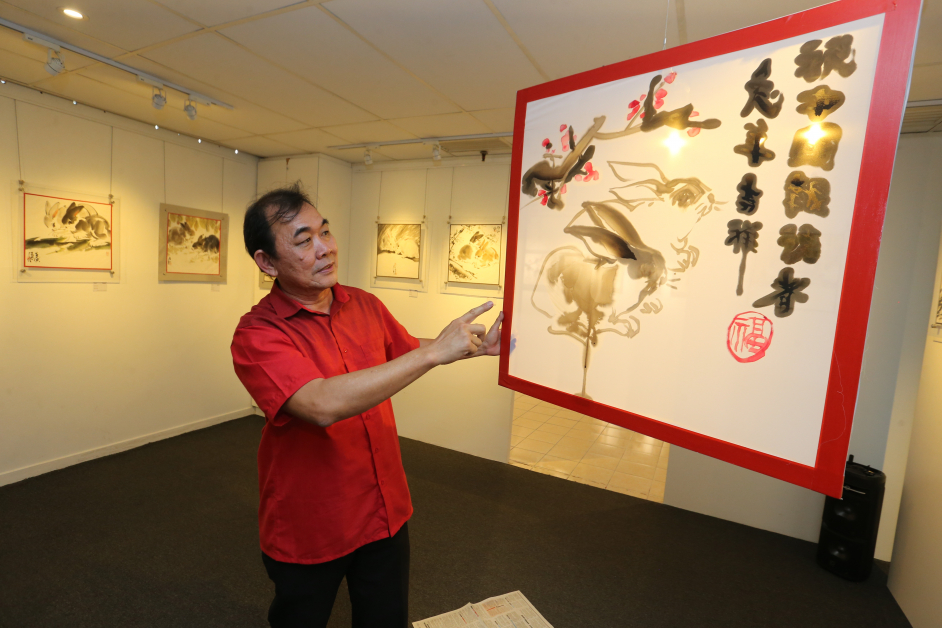 郭温和示范“灯下取影”，现场画一对玉兔向《中国报》读者贺年。