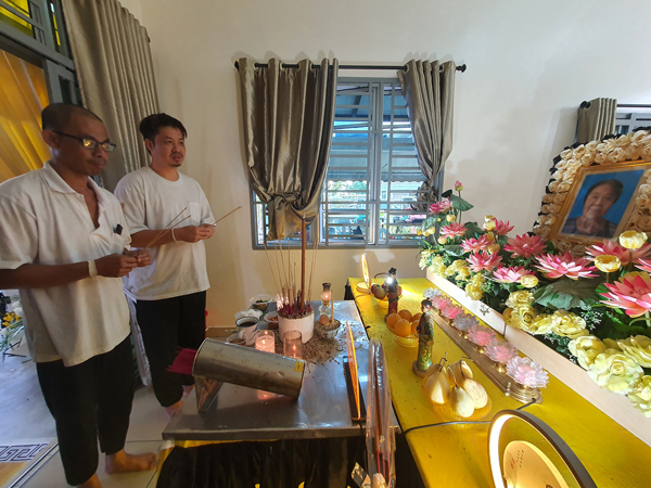 洪光伦（左起）及洪光俊在灵堂前拜祭母亲。