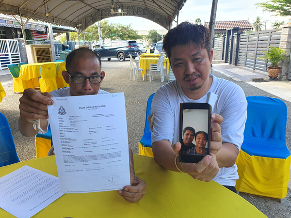 洪光伦（左起）及洪光俊向媒体展示报案纸及母亲生前的照片。
