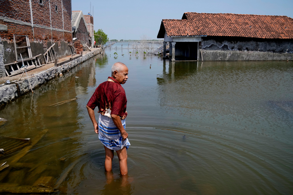 印尼中爪哇提姆布尔斯洛科村一名男子苏卡曼，望着屋子外被洪水淹没的走道，彷徨无助。（美联社）