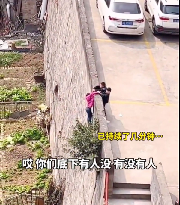 一名女童悬挂围墙外，2名小孩捉紧女童。