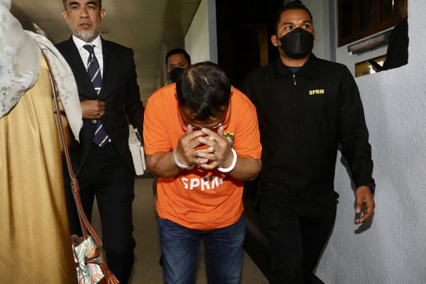莫哈末胡先（左3）在离开法庭时，掩面躲避媒体镜头。