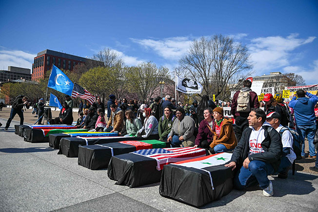 美国有数百名反战人士周六在白宫外举行反战集会，一些集会人员还抬着盖有一些国家国旗的“棺材”模型。（法新社）