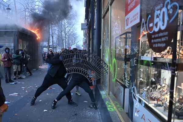 情绪激动的示威者在巴黎拿起一片人行道隔离铁花，企图撞破商店的玻璃窗。（法新社）
