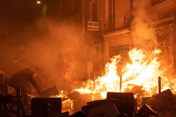 示威者周四在巴黎焚烧垃圾泄愤， 居民（左）和消防员尝试灭火。（法新社）
