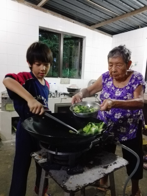 儿子小时候帮婆婆从锅里往碗盛菜。