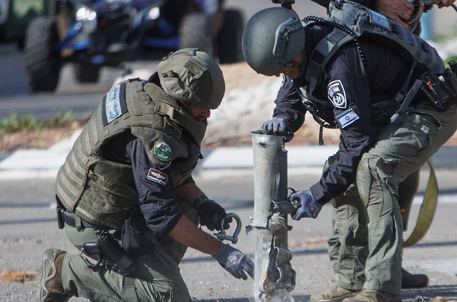 在以色列北部的什洛米镇，安全人员周四处理一枚火箭弹。（新华社）
