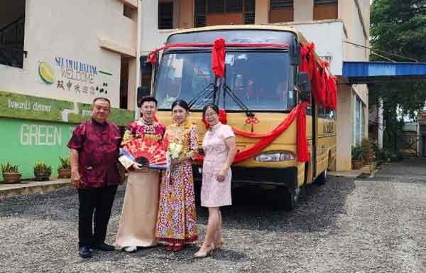 刘资鸿和妻子黄艺琳、父母刘宝华及郭美香，在复古布置的古老学校巴士前合照。
