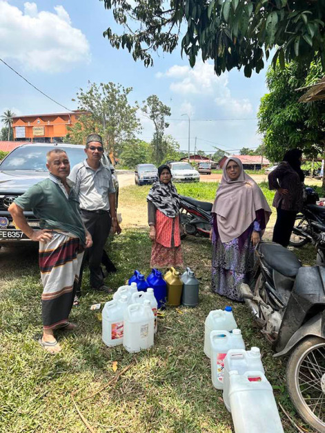 西蒂再拉（右）4月在其选区视察水供问题，民众带着空瓶子准备装水使用。