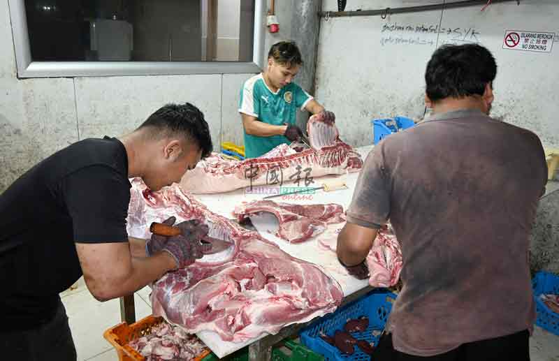 屠宰场工友正处理新鲜运抵的猪肉。


