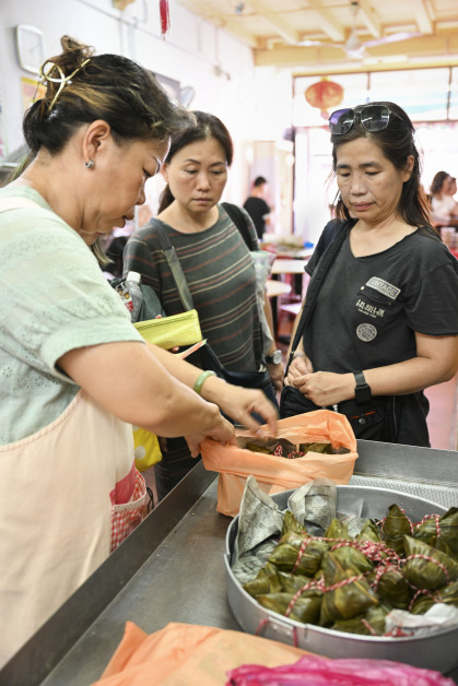 ▲马六甲河河畔一家粽子铺里，店长陈姷莲为顾客打包粽子。