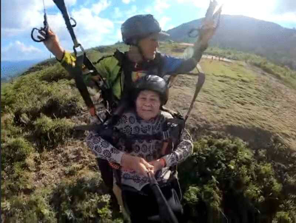汤老奶奶（前）在克里斯带领下，体验双人滑翔伞。