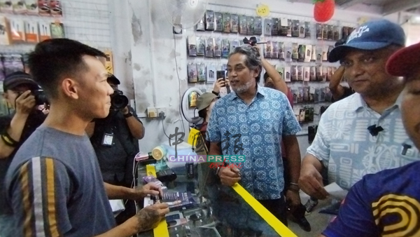 礼查马力肯（右起）与凯里在甲抛峇底市镇一带，逐间商店向当地选民拜票问好。
