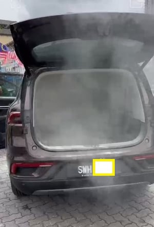 一辆宝腾X90休旅车疑电池爆炸，从车内冒出阵阵浓烟，车主将车门大开散烟。