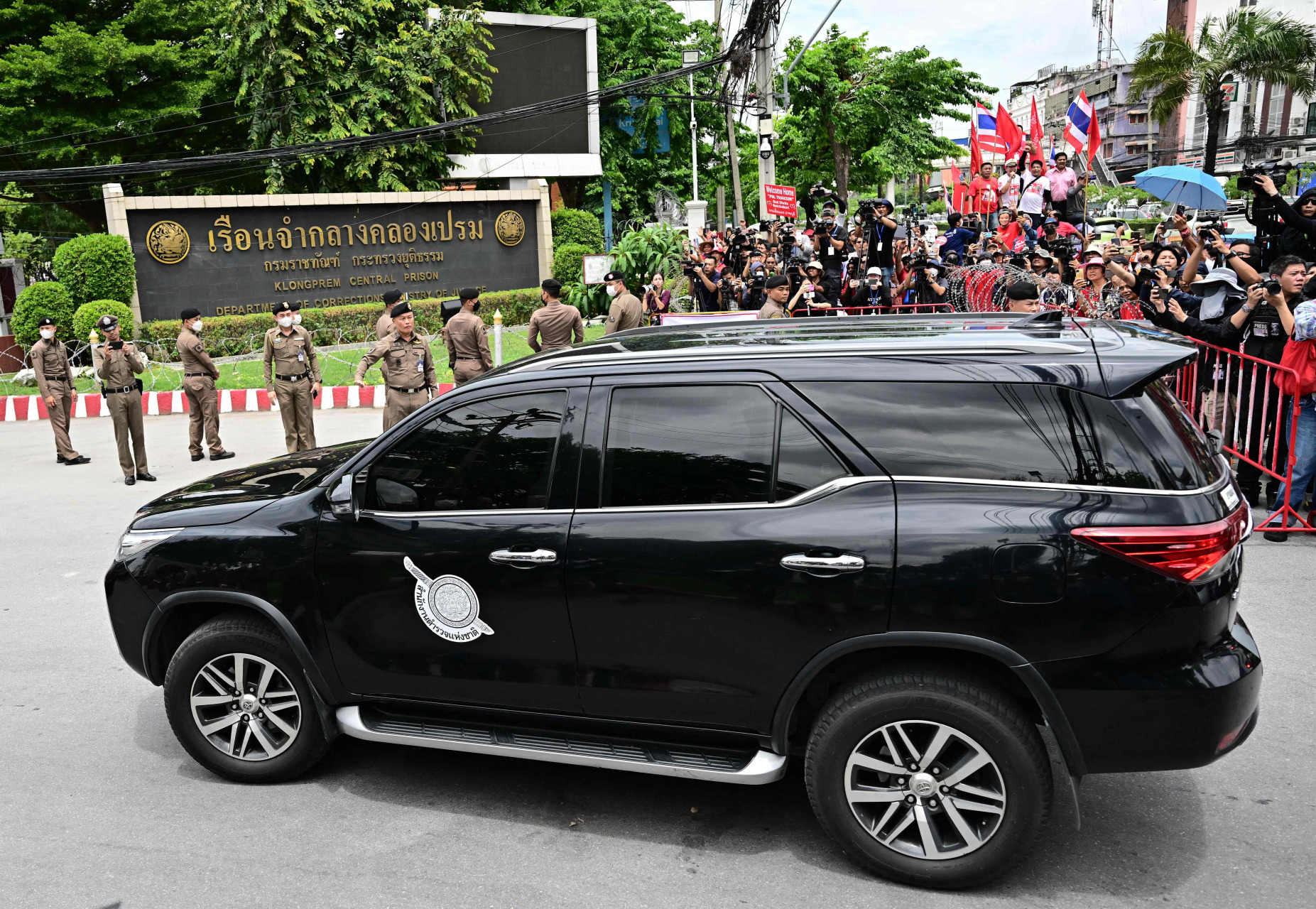 押送达辛的一辆黑色轿车， 前往曼谷一所监狱。（法新社）