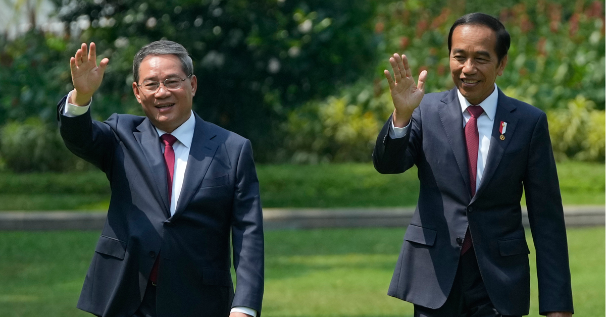 李强（左）和佐科威一起走在印尼总统府独立宫的草坪上，并向媒体挥手。（美联社）