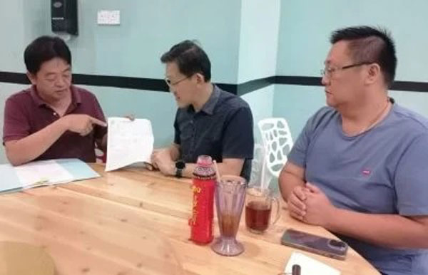 遭盗用身分和信用卡的许义华（左），在其社团副秘书张荣华（右）的陪同下，向薛华东（中）求助。