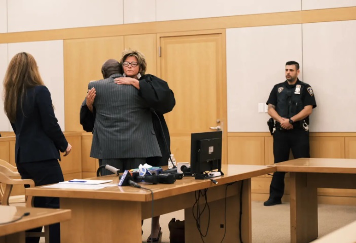 沉冤昭雪后，麦克（背对镜头者）在听证会上拥抱主审法官米尼汉。