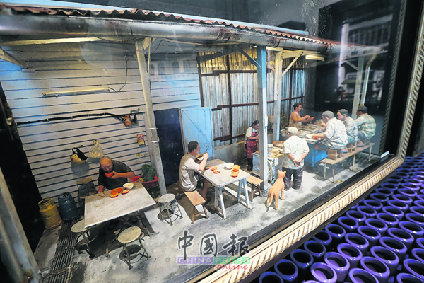 这份微雕作品中的食客坐在双重凳子上用餐，是槟城光大附近街道小食摊独有街景。