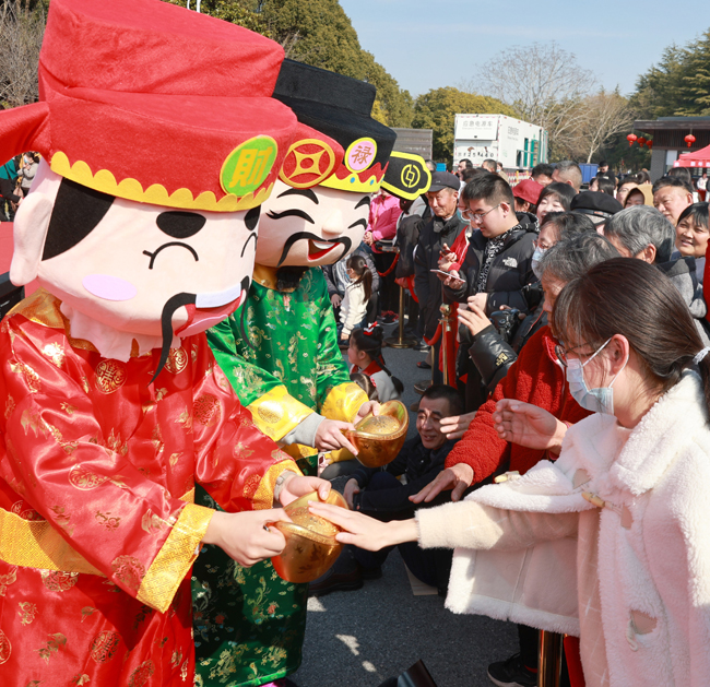 农历正月初五，“财神”在江苏南通狼山国家森林公园的民俗表演活动中，为游客送祝福。（新华社）