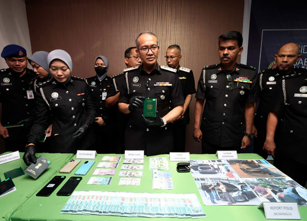 峇哈鲁丁（前排左4）展示移民局执法员所起获的各种物品，包括护照、现金和手机。（马新社）
