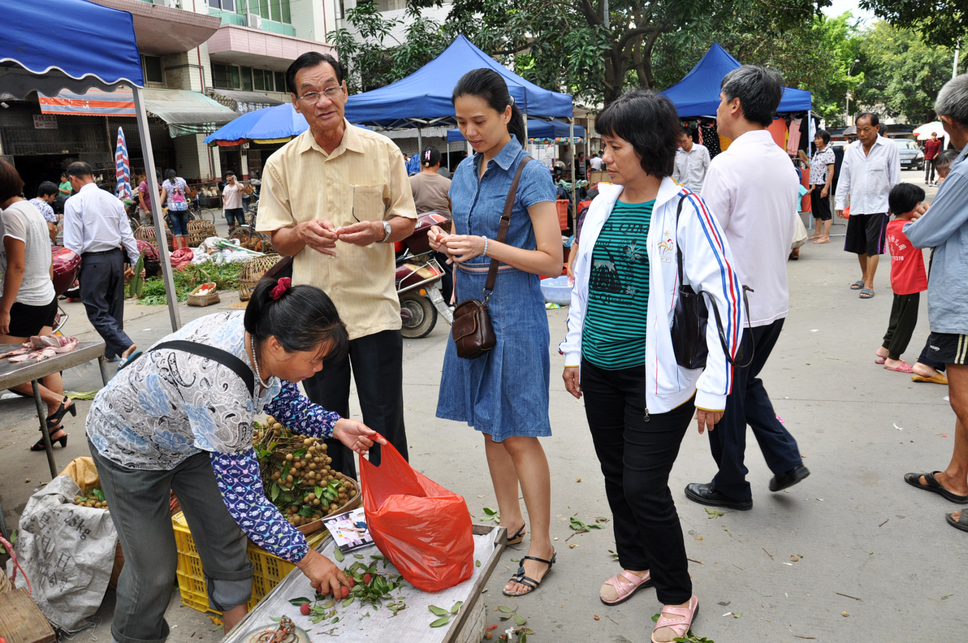 访问信宜期间，侨联会官员（中）带领温锦昌（左）和团员在信宜公市买水果。