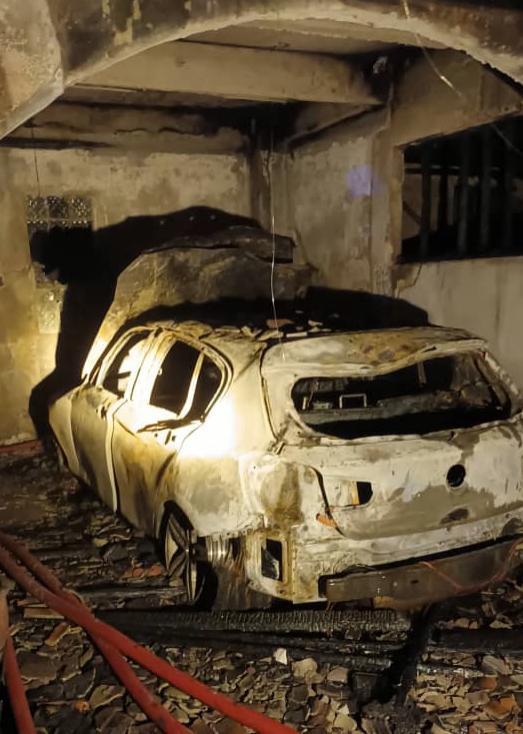 停泊在首间住家庭院的轿车，被烈火烧毁，只剩骨架。
