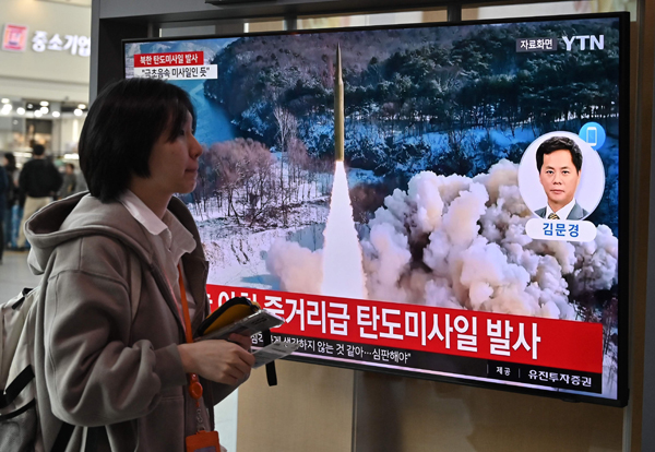 A woman walks past a television screen showing a news broadcast with file footage of a North Korean missile test, at a railway station in Seoul on April 2, 2024. North Korea fired a medium-range ballistic missile on April 2, Seoul's military said, the latest in a spate of banned weapons tests by Kim Jong Un's regime this year. (Photo by Jung Yeon-je / AFP)