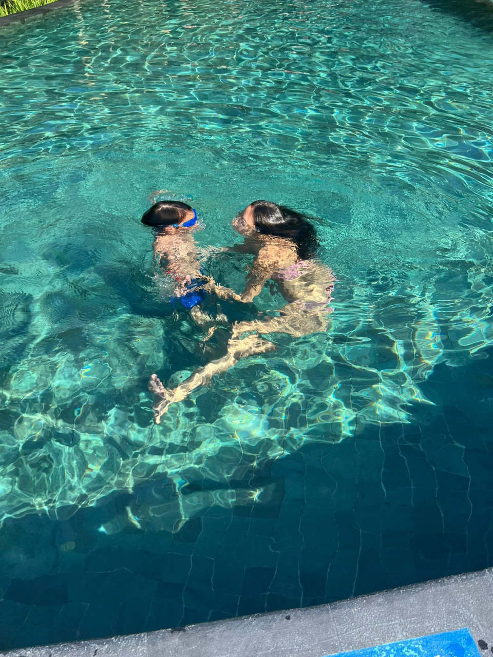 乐基儿与儿子在游泳池玩水。