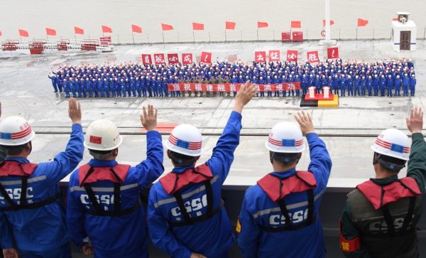 在上海江南造船厂码头送行的人群和福建舰出海试验的工作人员相互挥手告别。（新华社）