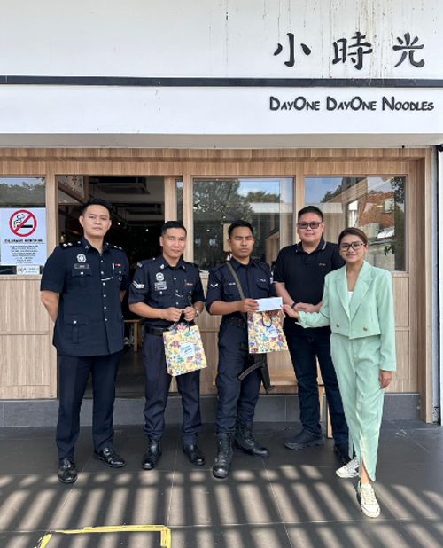 陈意尹(右起)在萧凯俊警官的见证下,将60令吉交给其中一名警员。