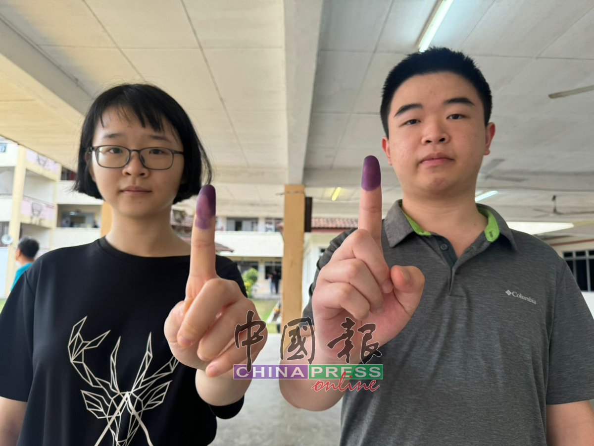 姚芯余和姚凯文兄妹，开心出示投下神圣一票的不褪色墨汁。