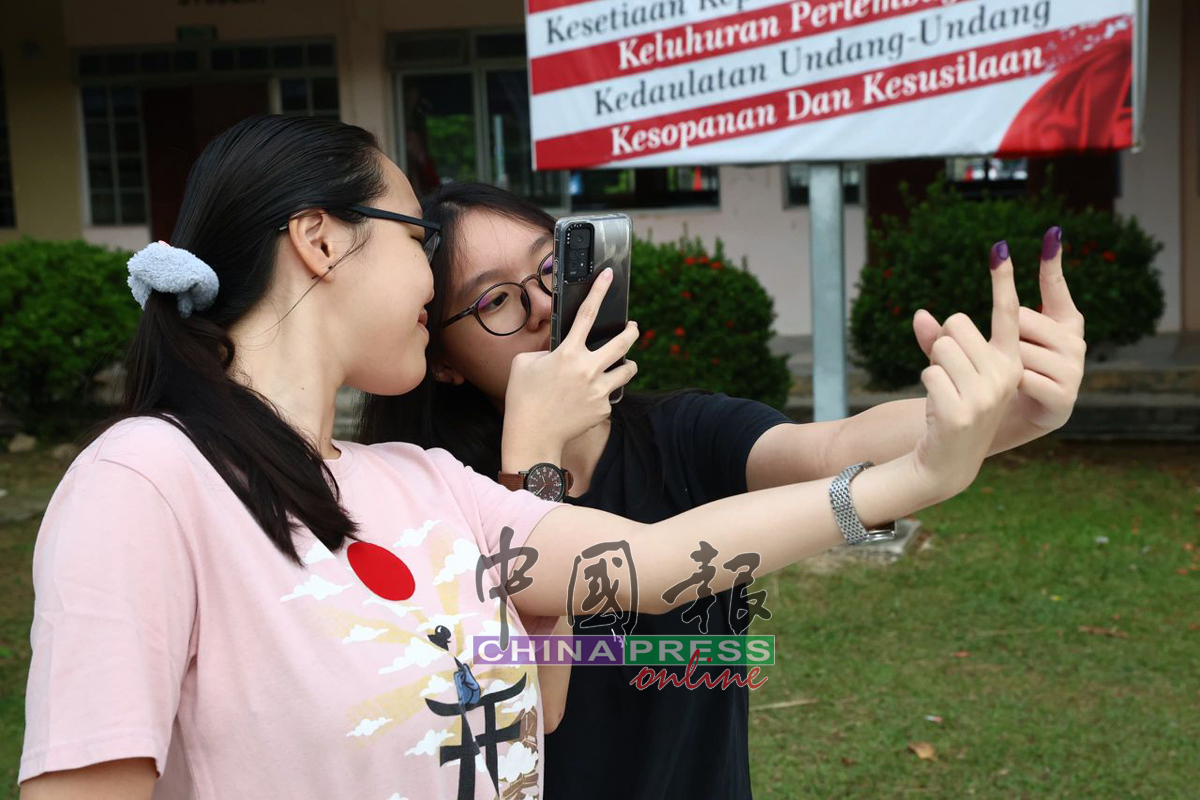 关靖潓与姐姐关靖颐，开心拍下印有不褪色墨汁的手指，为第一次投票留念。