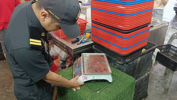 官员检查小贩使用的称重设备，发现没有存在问题。