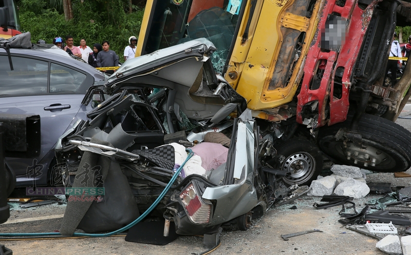 旧款宝腾赛佳轿车被罗厘太山压顶，死者紧紧夹在车座上惨死。
