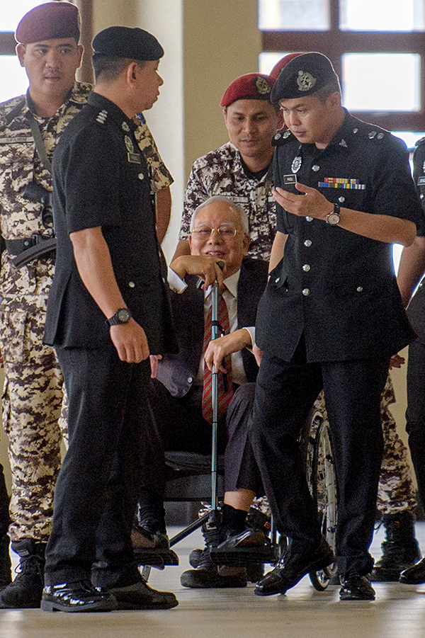 纳吉继续以轮椅代步，在监狱局官员推送下进入高庭。