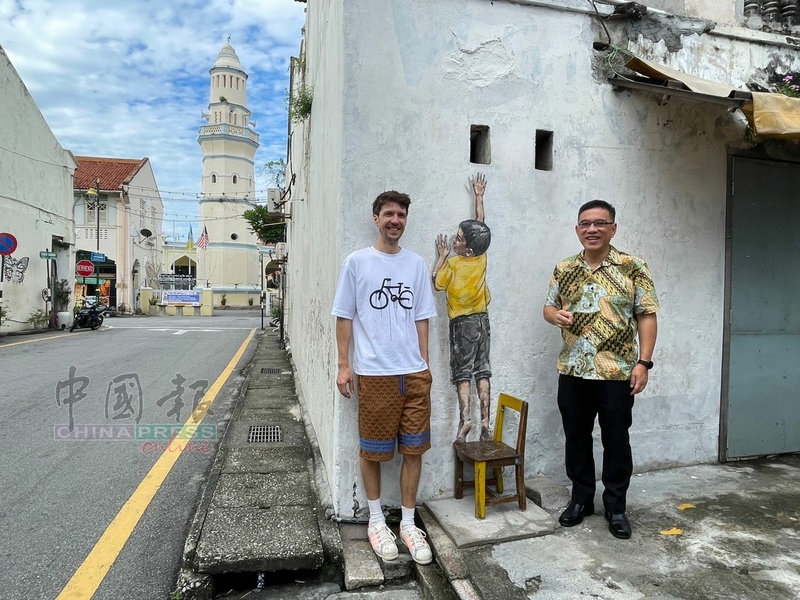 恩纳斯（左起）与黄汉伟，前来查看已完成修复的爬墙小孩壁画。
