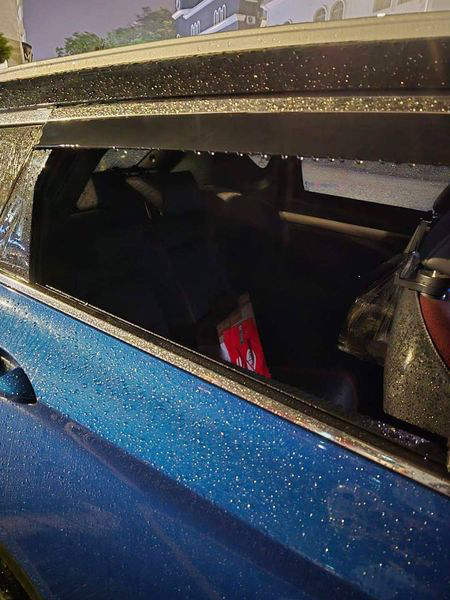 一辆蓝色轿车的后座车窗被砸破，车内一片狼藉。