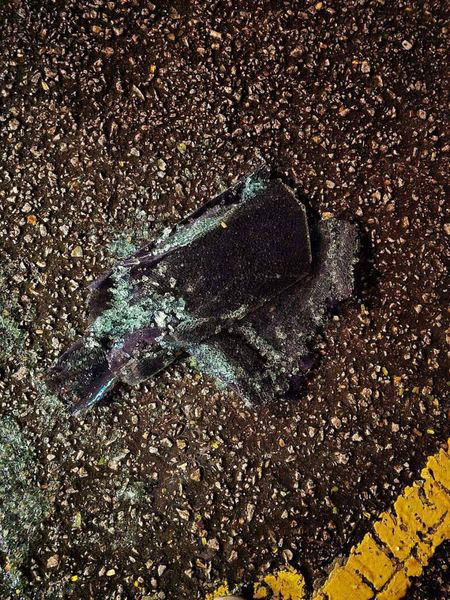 一辆蓝色轿车的后座车窗被砸破，车内一片狼藉。