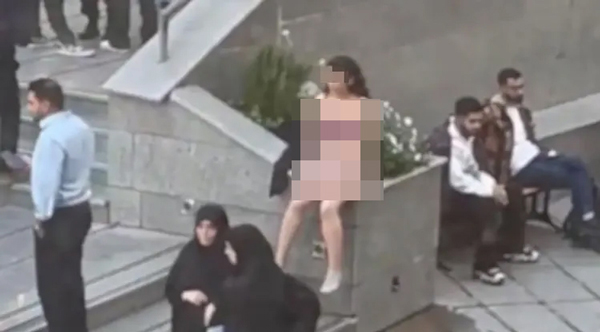 在寒风中，伊朗女大生于校园内脱到只剩内衣裤，孤单地抗议伊朗当局针对女性的严苛服装规定。前方2名黑衣女性为标准穿着。