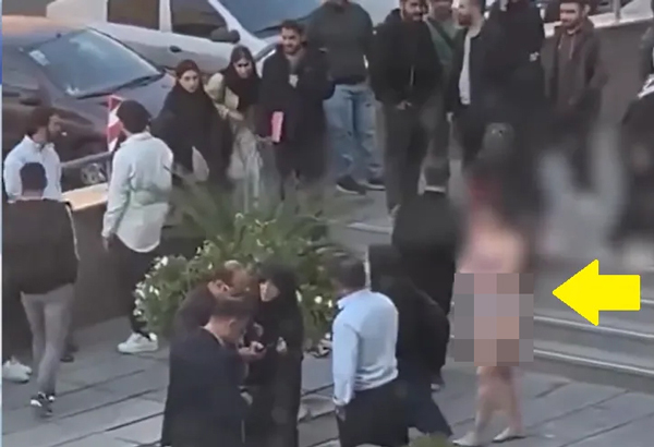 伊朗女大生独自一人（黄箭头）抗议服装规定，校园中其他人冷眼旁观。
