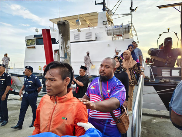 诺哈斯鲁与其家属，从巡逻船甲板缓缓步行至陆地，并被医护人员安排做进一步检查。