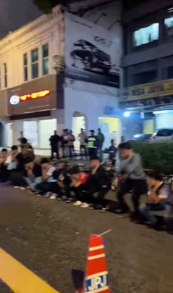 逾20名少年在警方的监督下，在大街上罚蹲。
