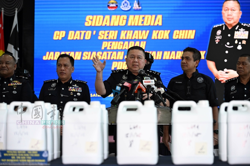 许国振（中）向媒体展示警方起获嫌犯使用的各种炼毒工具和原料。
