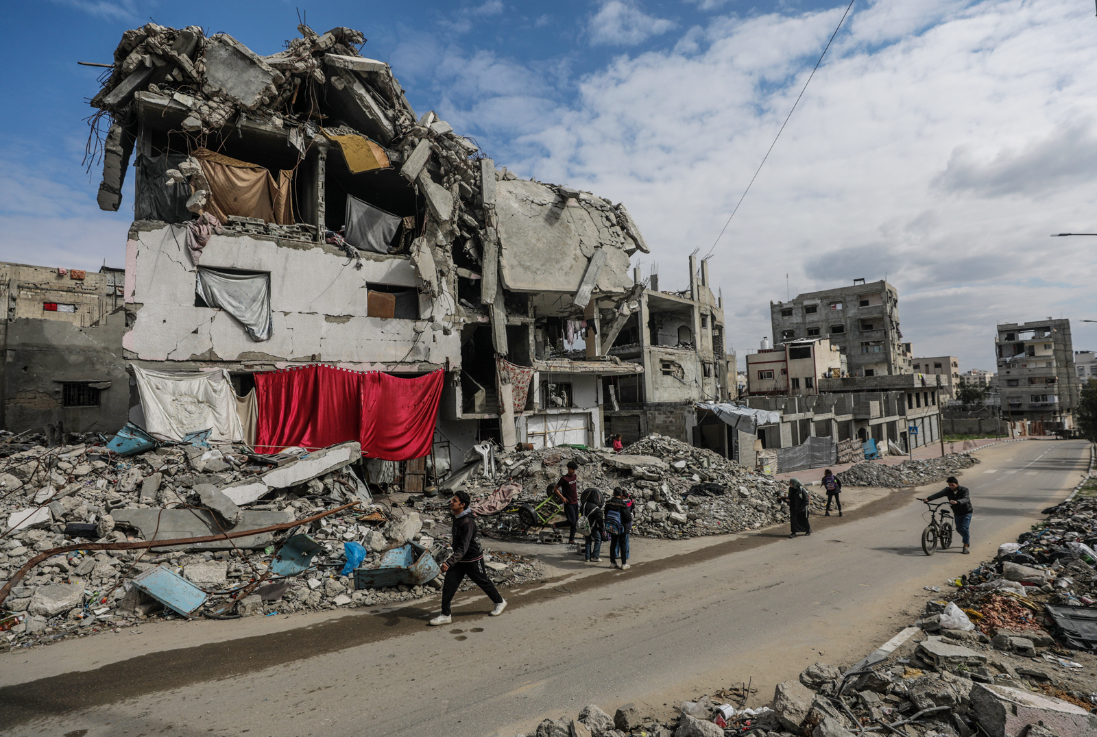 巴勒斯坦加萨人在以哈冲突期间，走过毁坏不堪的房屋。