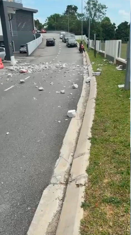 泊车场围墙被猛烈撞击后，许多瓦砾也跌落在马路上。