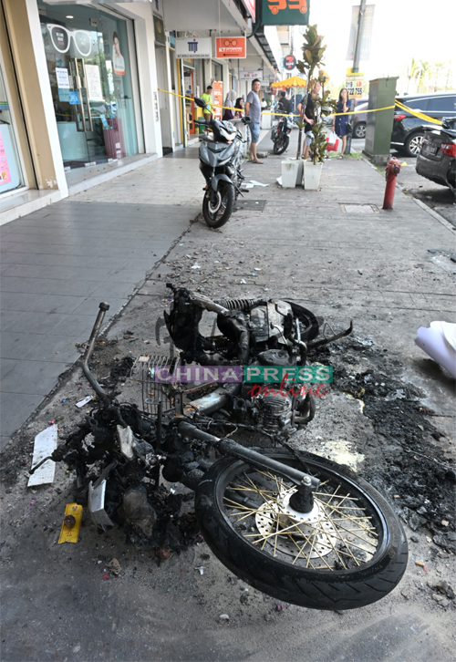 一辆焦黑的摩哆残骸躺在地上。