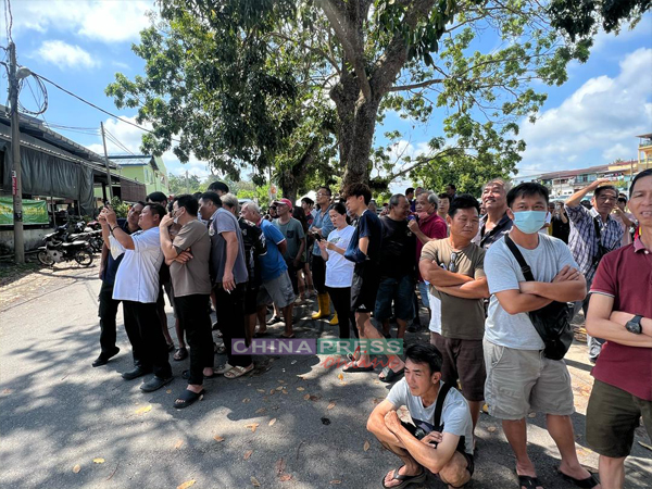 农民们聚集在路旁，从远处眺望榴梿树被砍伐，每人皆深感无奈。